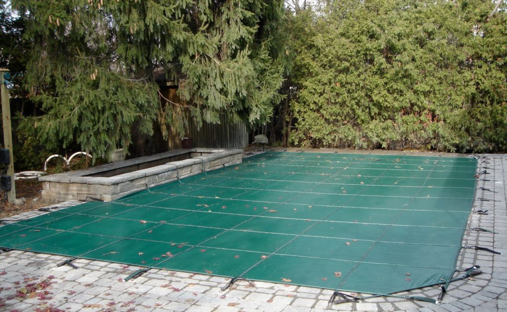 Closed in-ground pool with solid safety cover.